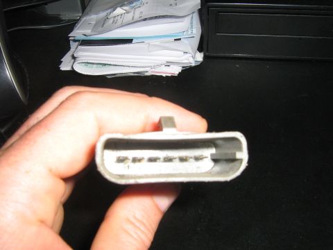 1990 Ford Bronco - A hand holds a gray electrical connector, showing its internal pins.