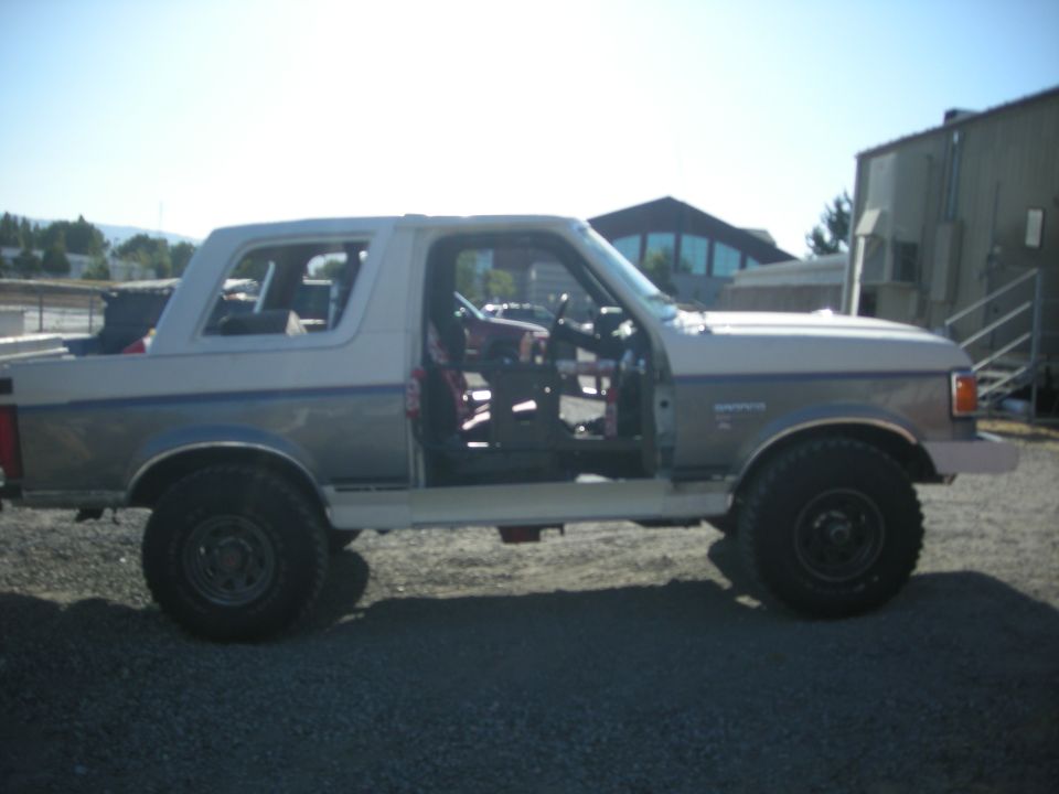 1991 Ford Bronco side view, doors removed, parked on gravel