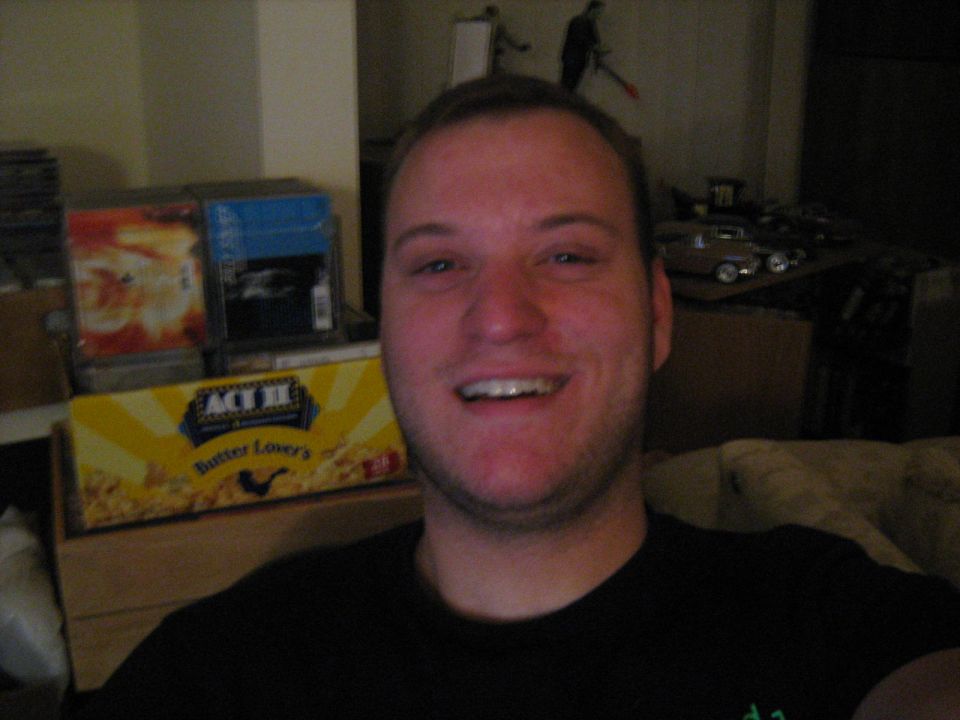 Smiling young man in a dark shirt seated in a living room