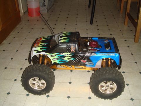 1992 Ford Bronco - This remote-controlled monster truck features flame graphics and a blue bed with the name 'Wolverine' visible.