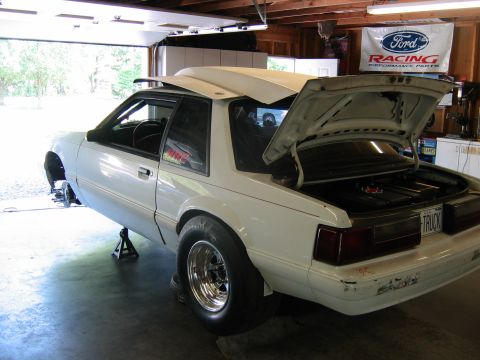 1992 Ford Mustang - A white 1992 Ford Mustang is parked in a garage with its hood and trunk open, resting on jack stands.