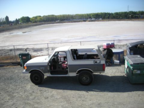 1991 Ford Bronco - This two-tone Ford Bronco is parked outside with its doors open, revealing the interior.