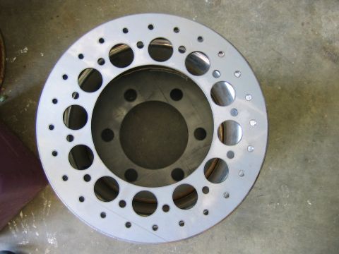 1992 Ford Mustang - A drilled brake rotor is shown from a top-down perspective on a workshop floor.