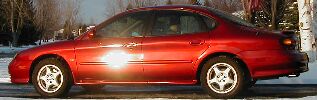 1997 Ford Taurus - A red 1997 Ford Taurus is shown from the side, with trees and snow in the background.