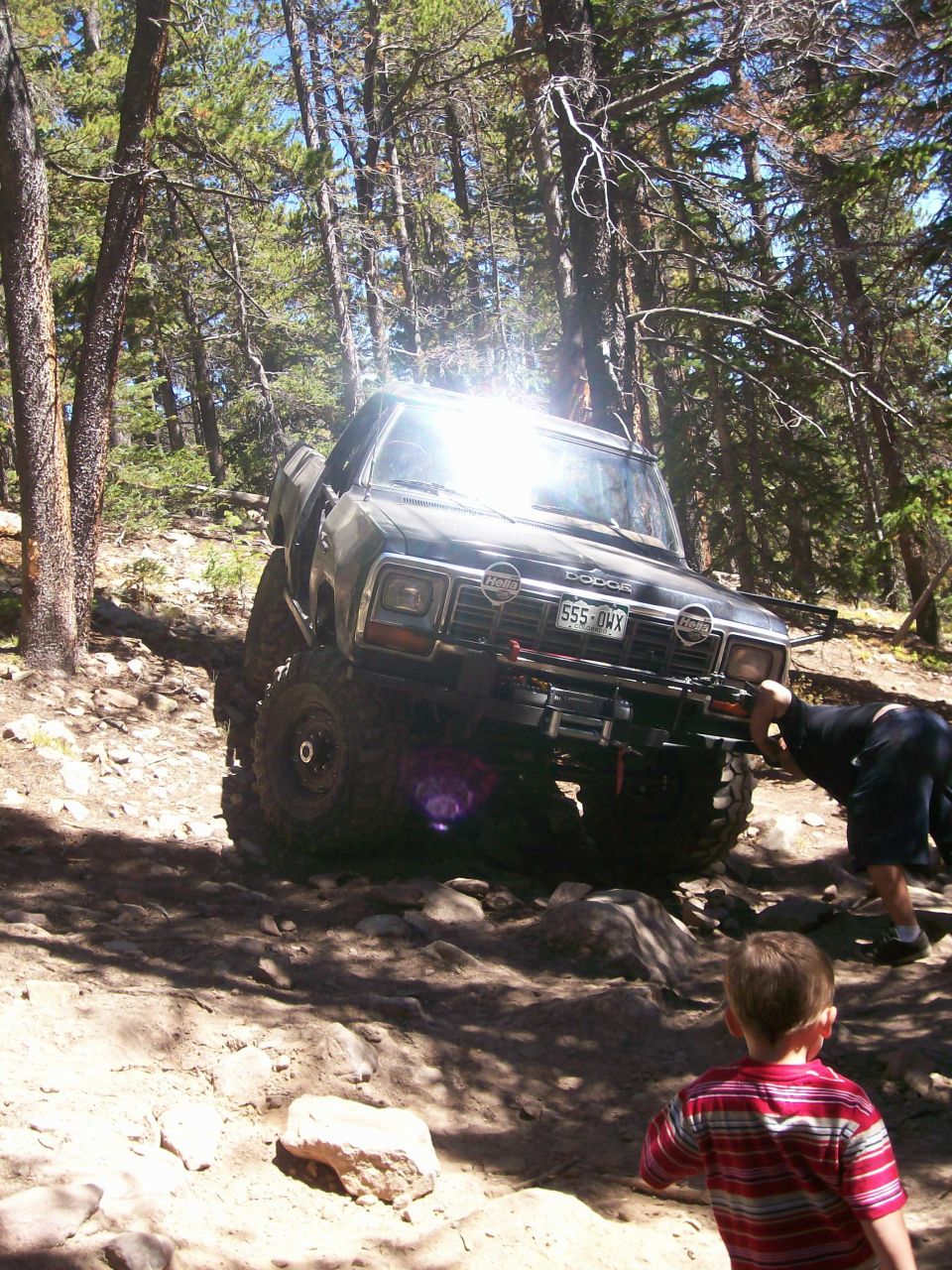 Lifted Dodge pickup truck on a rocky trail with a boy watching.