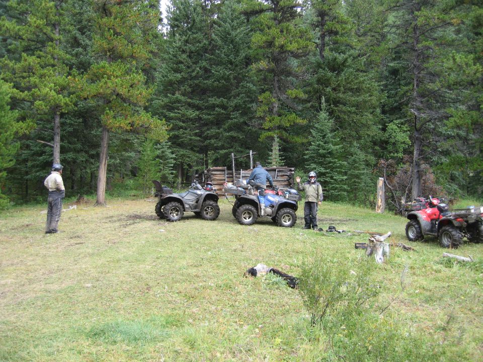 Two ATVs parked in a forest clearing with a person standing next to one.