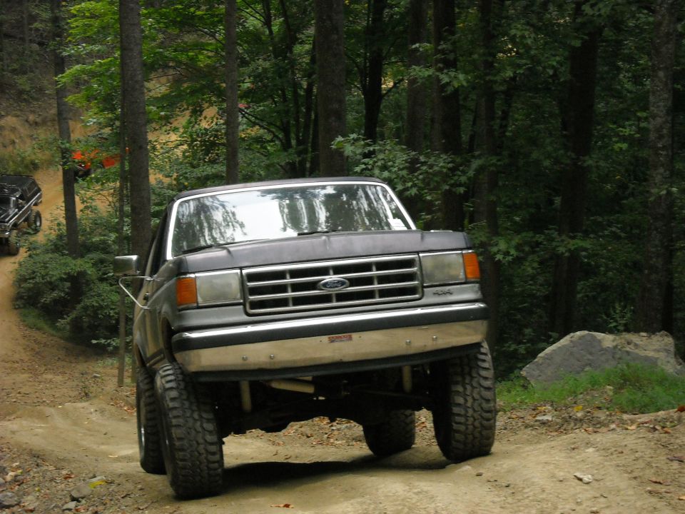 Gray Ford truck climbing a dirt trail through the forest