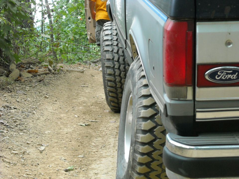 Close rear-quarter view of a silver Ford Bronco tire on a dirt trail