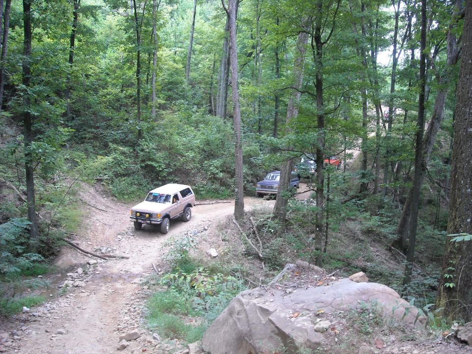 White SUV on a rocky dirt trail in a wooded ravine