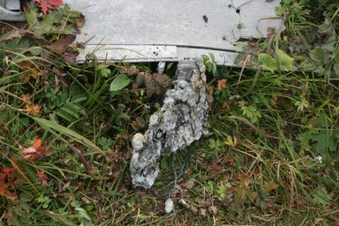 1990 Chevrolet Suburban - A close-up of a vehicle part is seen against a backdrop of greenery.