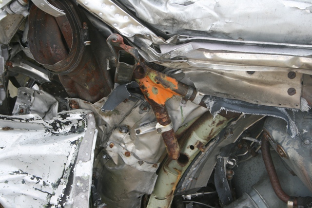 Close-up of mangled and rusted aircraft wreckage, showing bent metal and structural components.