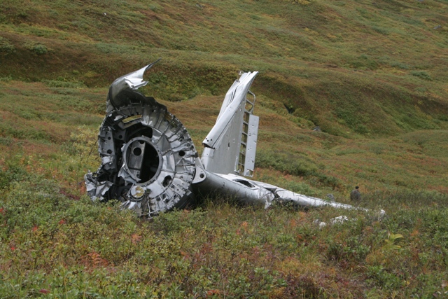 Airplane wreckage on a grassy hillside.