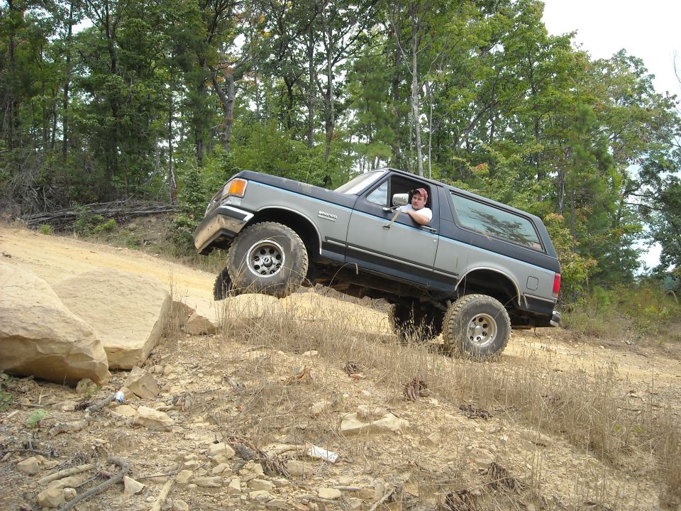 Blue full-size Ford Bronco climbing a steep dirt embankment off-road