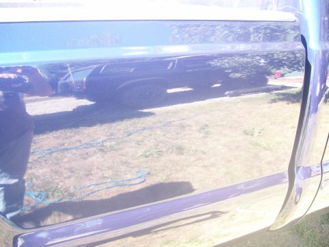 1978 Ford Bronco - The reflection in the side panel of a dark blue SUV shows a black SUV with large tires and a visible exhaust pipe. A blue rope is visible o…