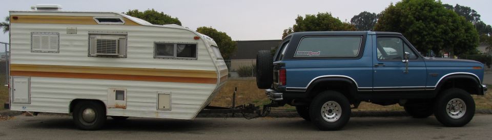 Blue 1980s Ford Bronco towing a travel trailer