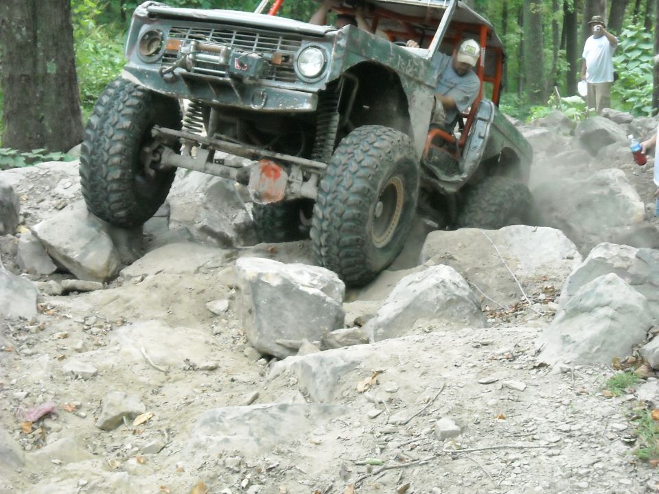 Ford Bronco wheeling over boulders kicking up dust