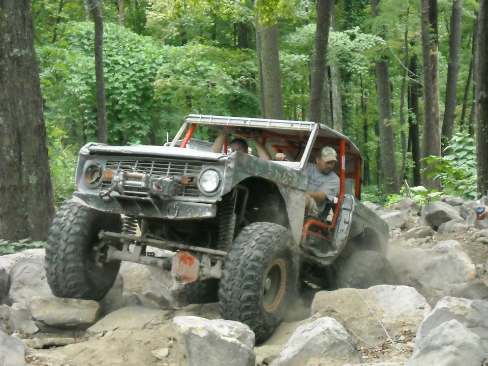 Ford Bronco crawling over boulders with driver visible