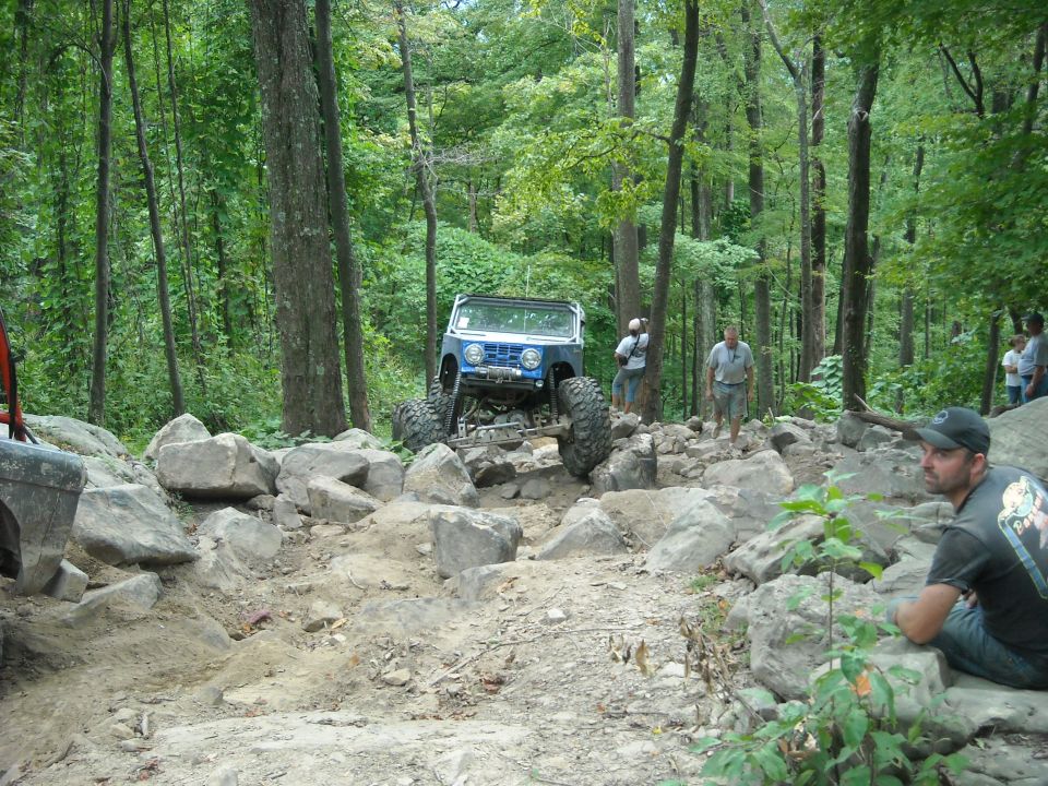 Blue Ford Bronco crawling distant rocks with spectators