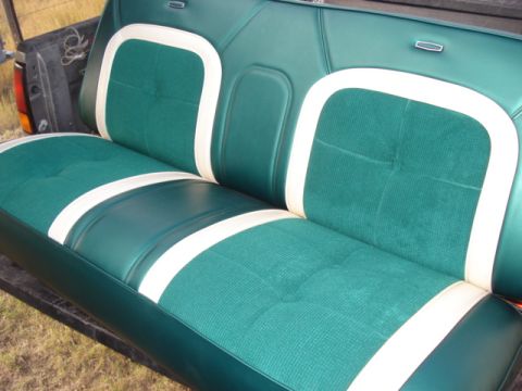 1979 Ford F-150 - A close-up view of the green and white upholstered bench seat of a classic pickup truck. The seat features a tufted design with white pipin…
