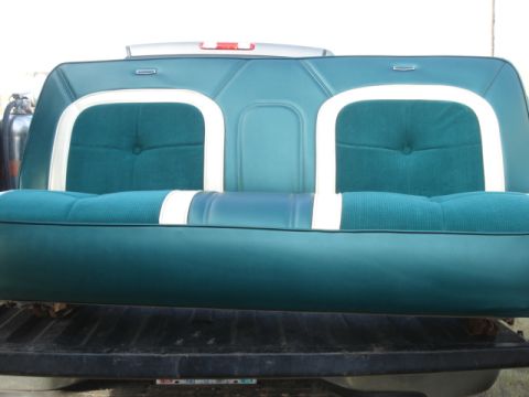 1979 Ford F-150 - A teal and white upholstered bench seat, likely from a vintage vehicle, is shown from the front. The seat has a tufted pattern and white pi…