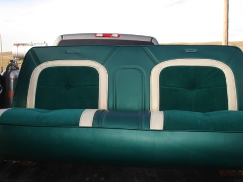 1979 Ford F-150 - A close-up rear view of a green and white upholstered bench seat, likely from a classic truck, is shown outdoors.