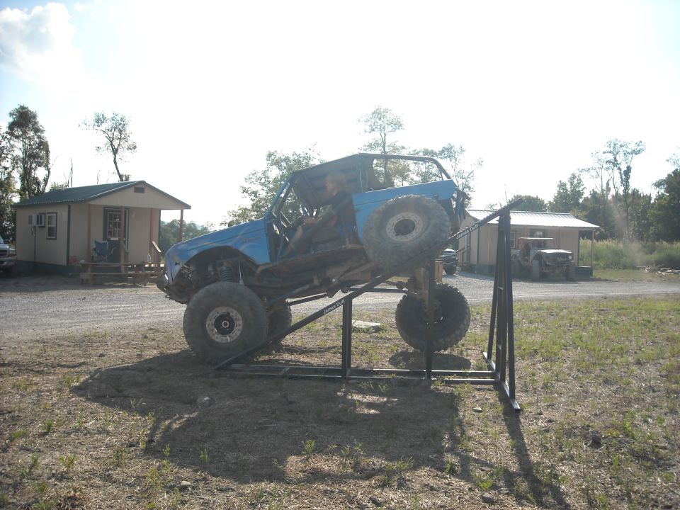 Blue off-road buggy balanced on a steel teeter-totter ramp obstacle