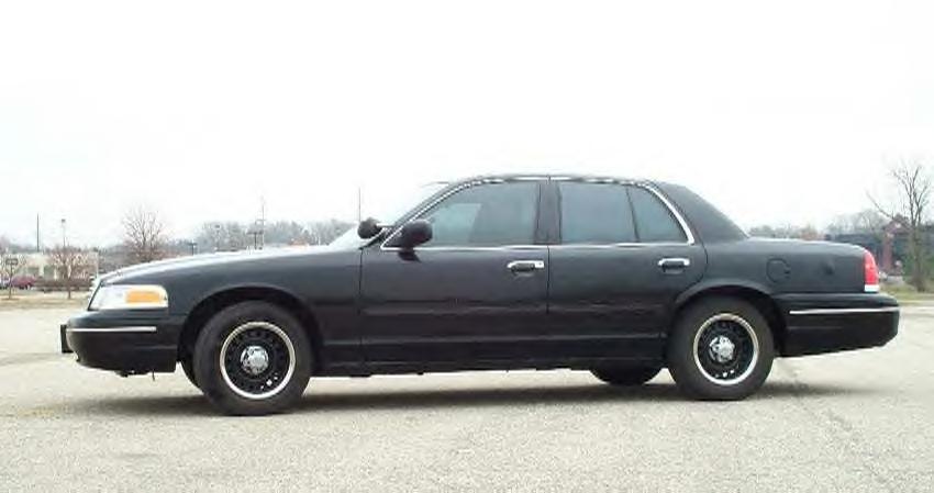 Black Ford Crown Victoria sedan, driver-side profile, black steel wheels, parked on empty lot