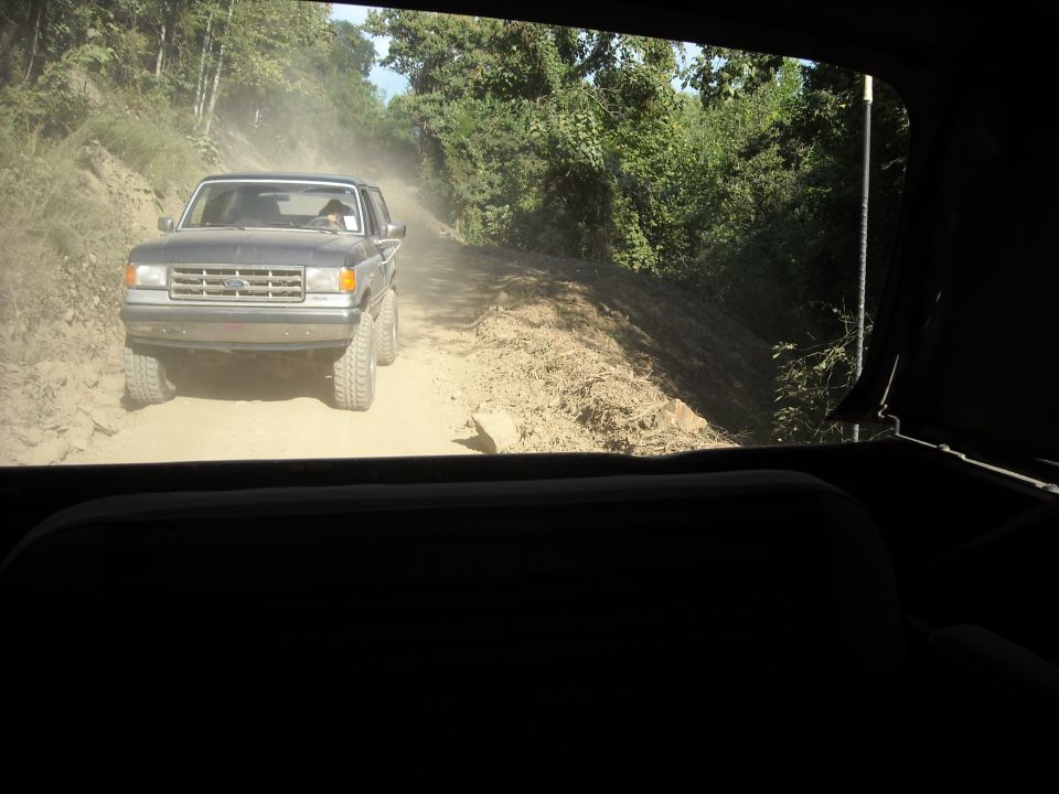 Ford truck on a dusty dirt road seen through a vehicle window