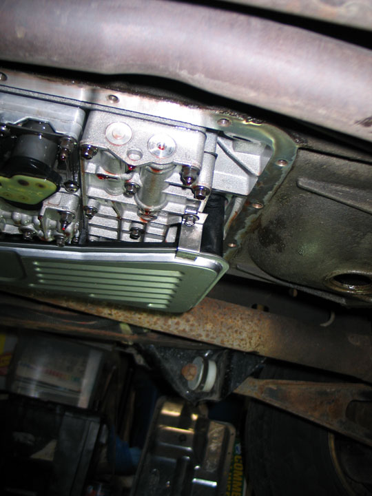 Transmission pan removed, showing filter and valve body with reddish-brown fluid.
