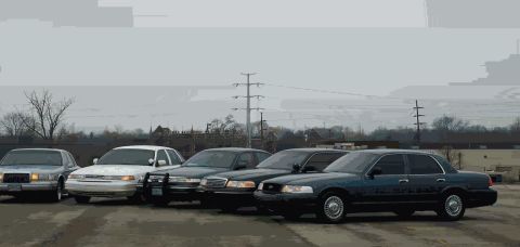 1988 Ford Crown Victoria - A group of Ford Crown Victoria police cars are lined up outdoors under a cloudy sky.