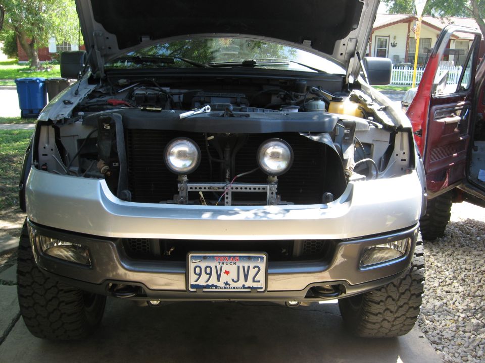 Silver pickup truck front view, hood open, aftermarket lights, Texas license plate