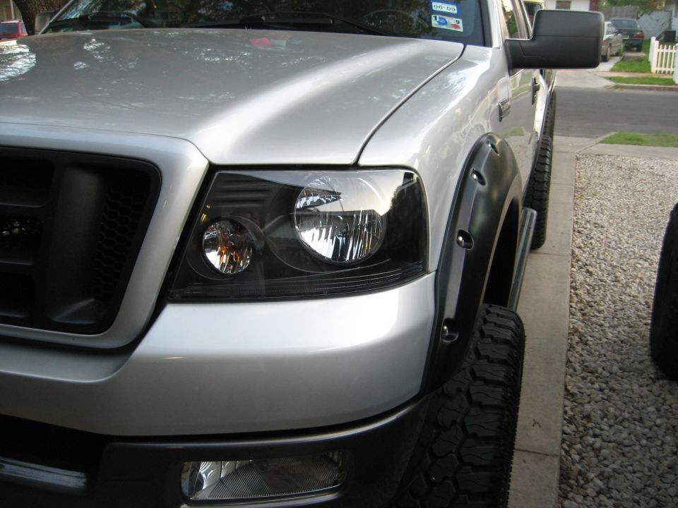 Silver pickup truck front fender and headlight assembly with black fender flares and large tires