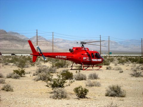1996 Ford Bronco - A red helicopter with visible registration and text sits in a desert landscape under a clear blue sky.