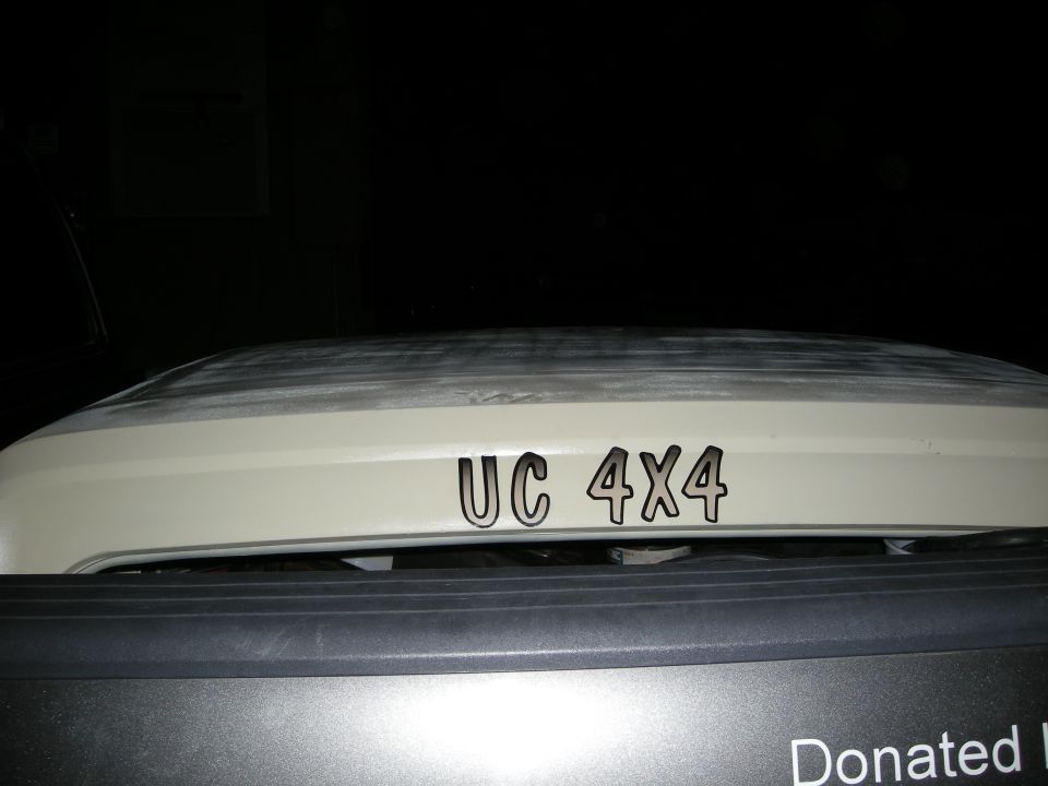 Hood of a vehicle with 'UC 4X4' decals. Part of a dark grille is visible below