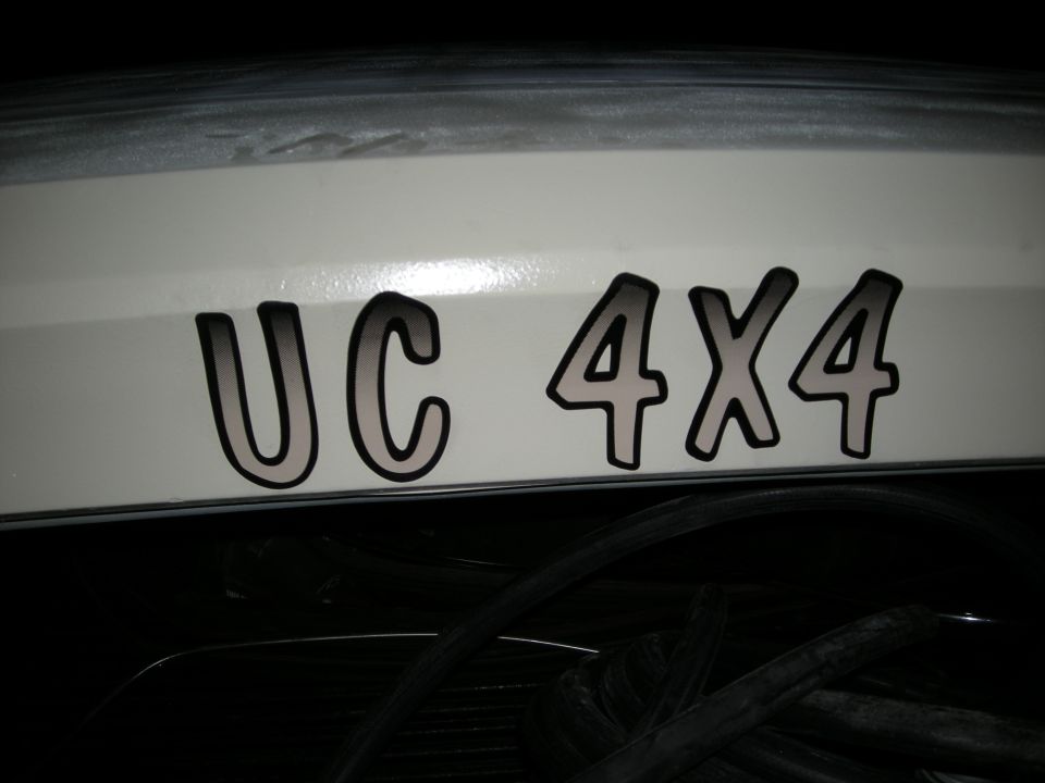 White vehicle rear with UC 4X4 decal. Dark interior visible below