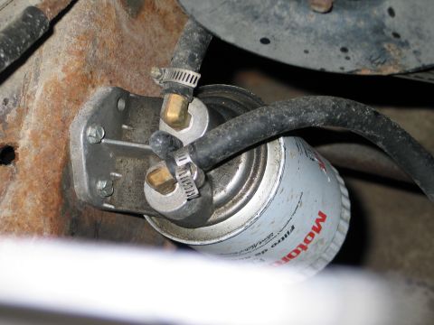 1994 Ford Bronco - This is a close-up view of a vehicle's fuel filter, showing its hoses and mounting bracket.