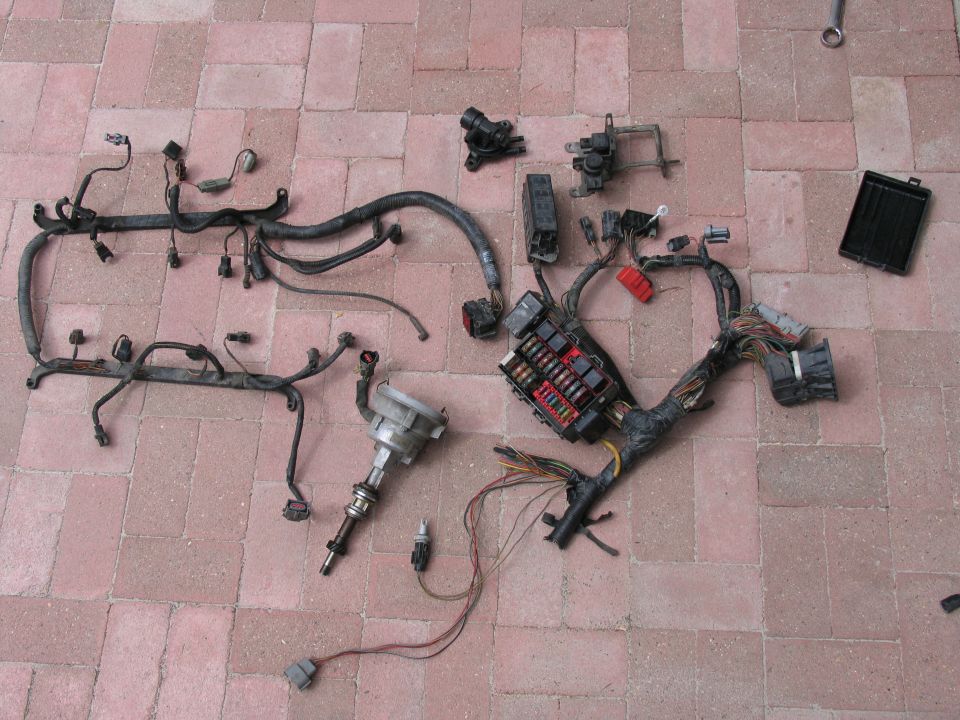 Engine wiring harness, fuse box, distributor, and other engine parts laid out on a brick surface