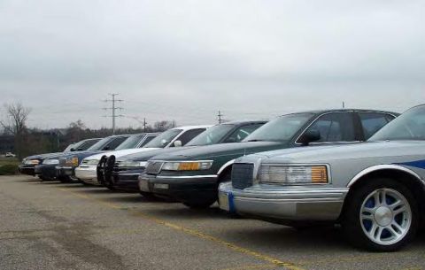 1988 Ford Crown Victoria - Several sedans are parked in a row on a cloudy day.