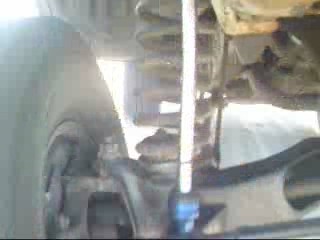 1984 Ford Bronco - This is a close-up, low-angle shot of the suspension system of a vehicle, likely a 1984 Ford Bronco. Visible components include a coil spri…