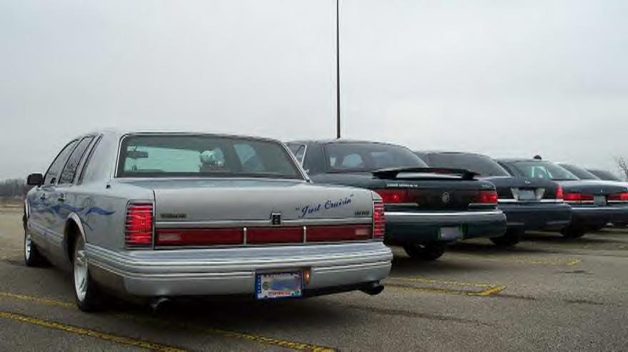 Lowered silver Lincoln Town Car with blue flames and Just Cruisin trunk script, rear 3/4 view