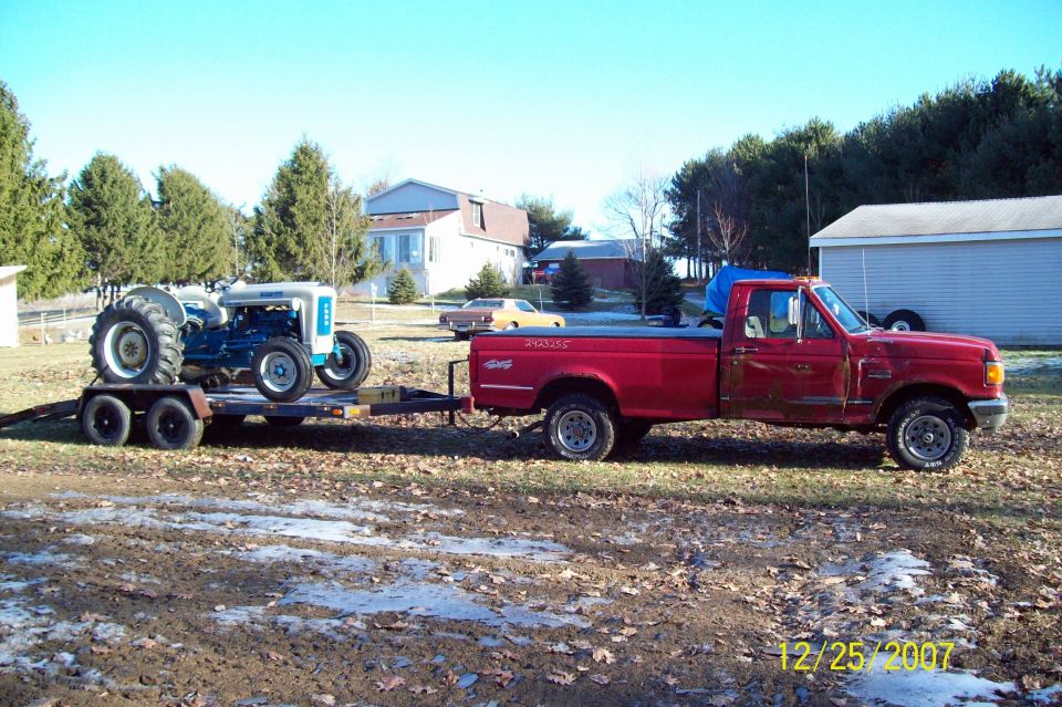 Red Ford F-150 towing a trailer with a tractor.