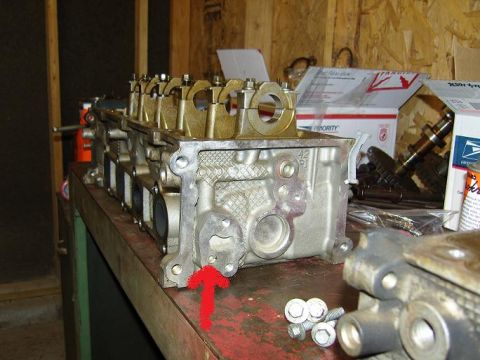 2007 Ford Mustang - Photograph of a cylinder head on a workbench with a hand-drawn red arrow, a physical part not a document.