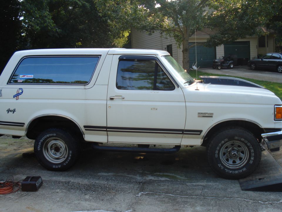 White 1991 Ford Bronco side view with black trim and hood accent
