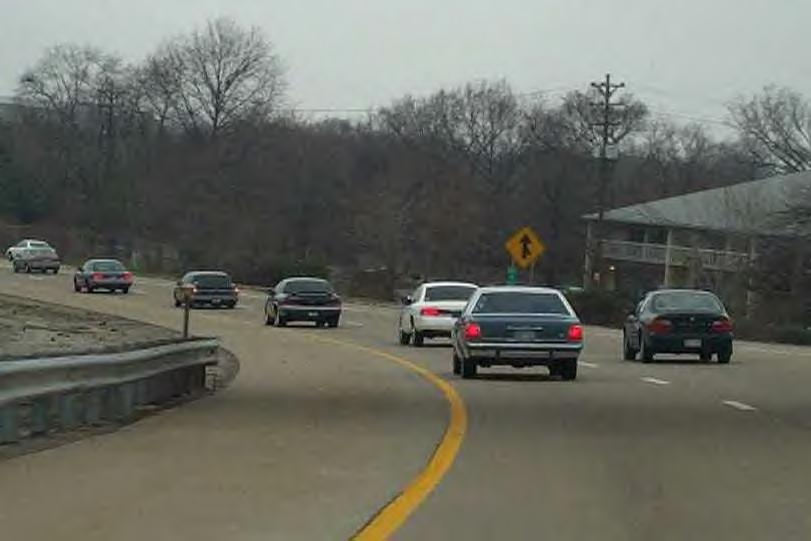 Highway scene with several cars including a white sedan, shot from a moving vehicle