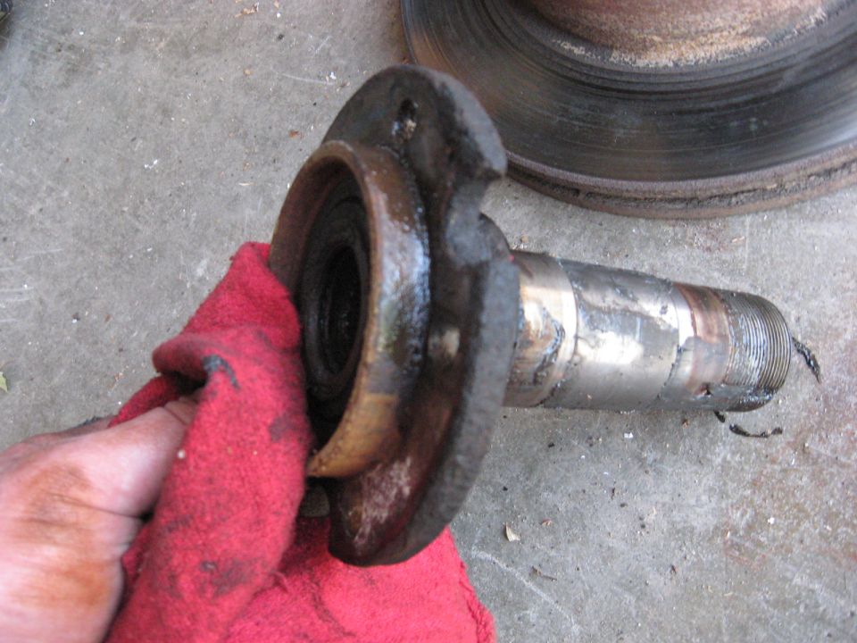 Greasy threaded spindle and brake rotor being wiped with a red rag.