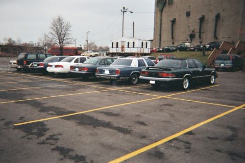 1988 Ford Crown Victoria - A dark-colored 1988 Ford Crown Victoria is parked in a lot with other vehicles.