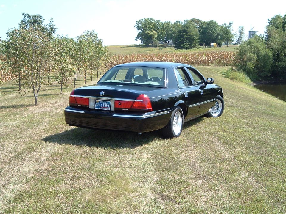 Black 2001 Mercury Grand Marquis parked on a grassy hill with a cornfield in the background.