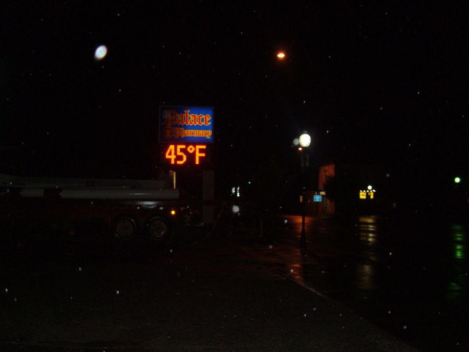 Digital thermometer showing 45 degrees Fahrenheit at night next to a pharmacy sign.