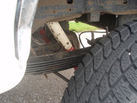 1987 Ford Bronco - A close-up view of the rear suspension and tire of a Ford Bronco, showing the leaf springs, shocks, and a portion of the tire tread. The ve…