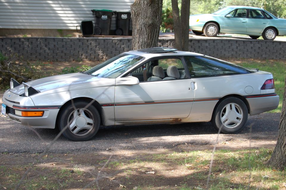 Silver 1991 Ford Probe with pop-up headlights raised, parked outdoors.